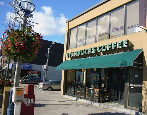 Green awning on tawny stucco building sits below a sign: STARBUCKS COFFEE