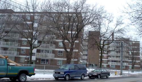 Two six-storey brown-brick buildings sit at an angle to a snowy street