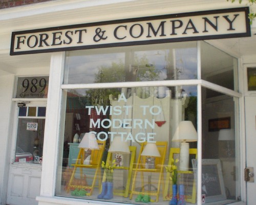 Black serif type reads FOREST & COMPANY on a white sign with black border. Letters on window read A TWIST TO MODERN COTTAGE