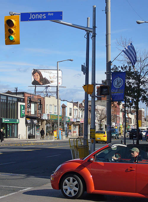 Man in red New Beetle convertible waits at intersection whose overhead sign reads Jones Ave