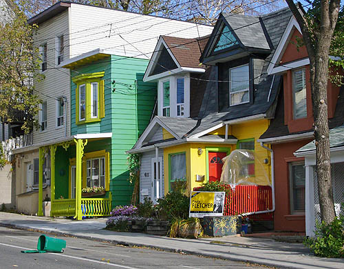 A bright green house with yellow trim, a normal semi, another green-and-yellow house with a red door