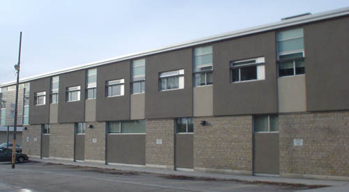 Two-storey building has brown panels in different textures and small punched windows