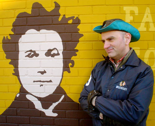 Me in trademark green Gore-Tex® hat and Girls Hockey jacket in front of Alexander Muir mural