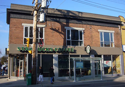 Brick building has stucco signage strap over ground floor reading STARBUCKS COFFEE